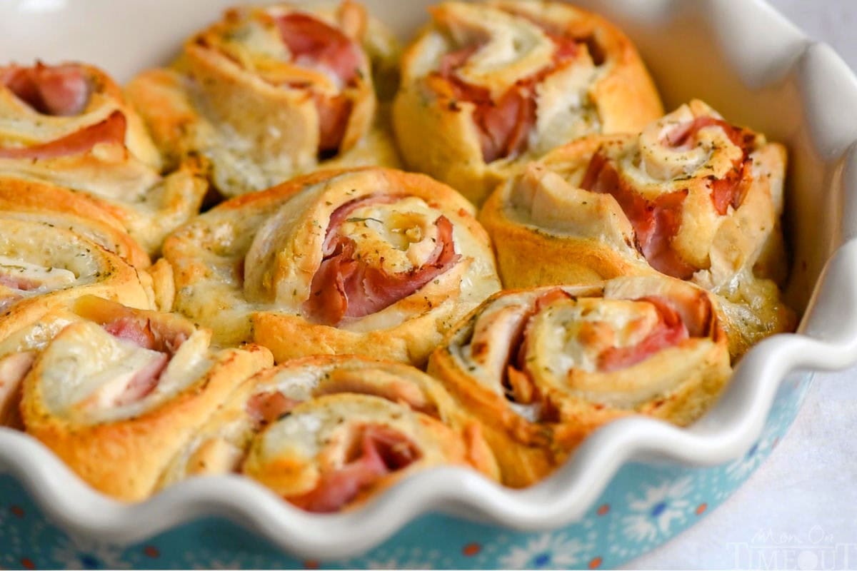 Wide shot of chicken cordon bleu crescent roll ups in a white pie dish.