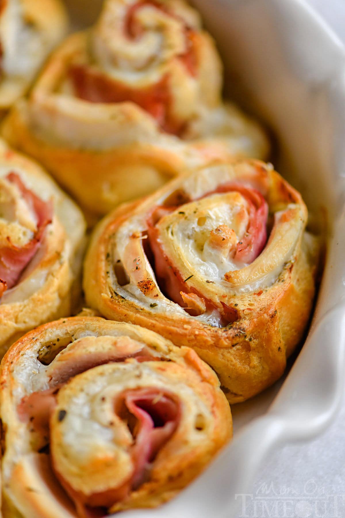 Chicken cordon bleu crescent rolls in white pie dish.