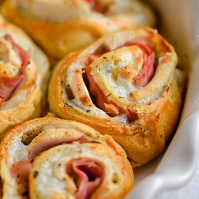 Chicken cordon bleu crescent rolls in white pie dish.