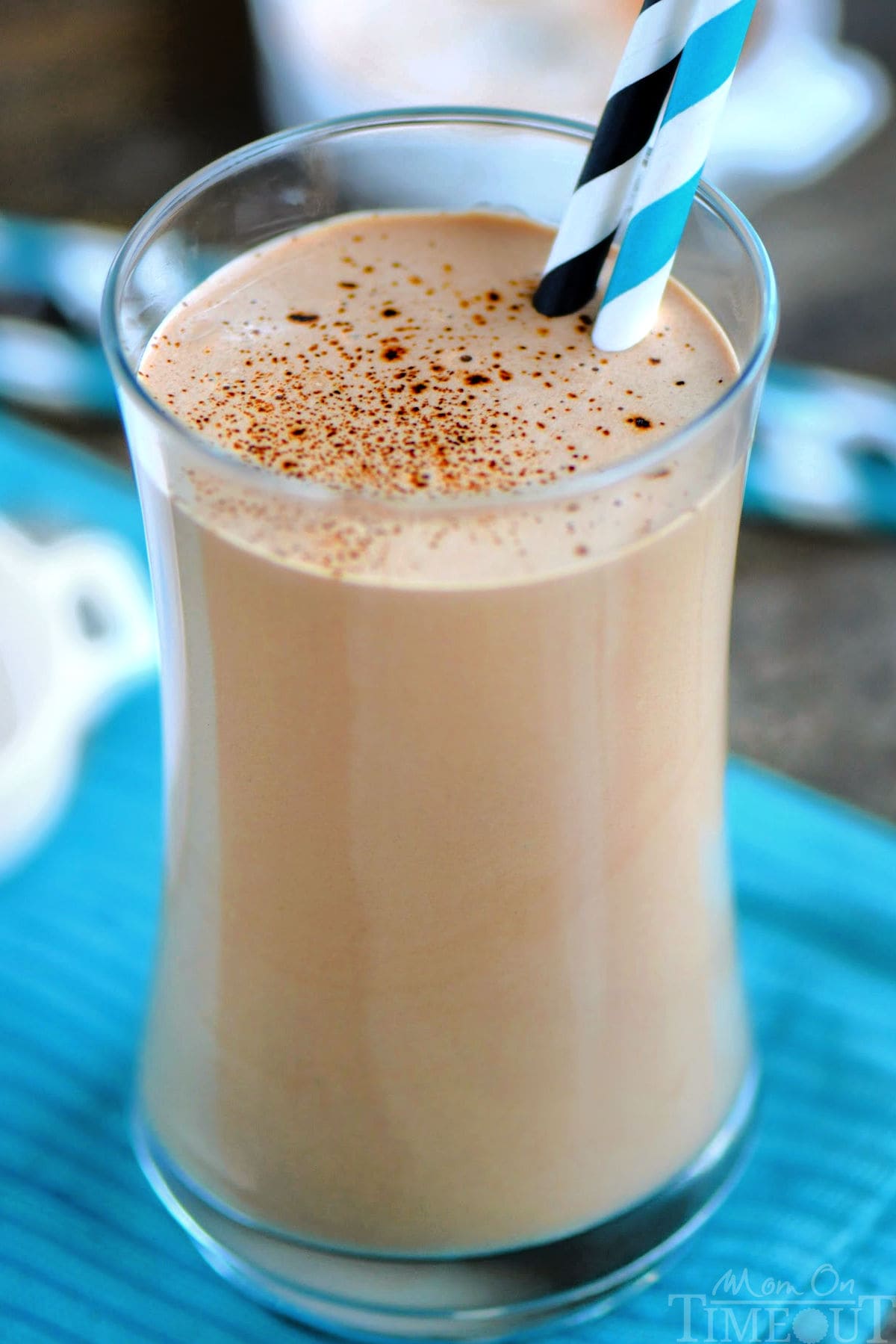 Up close look at coffee protein shake recipe in a tall glass ready to be enjoyed. You can see a sprinkle of espresso powder on top of the shake.