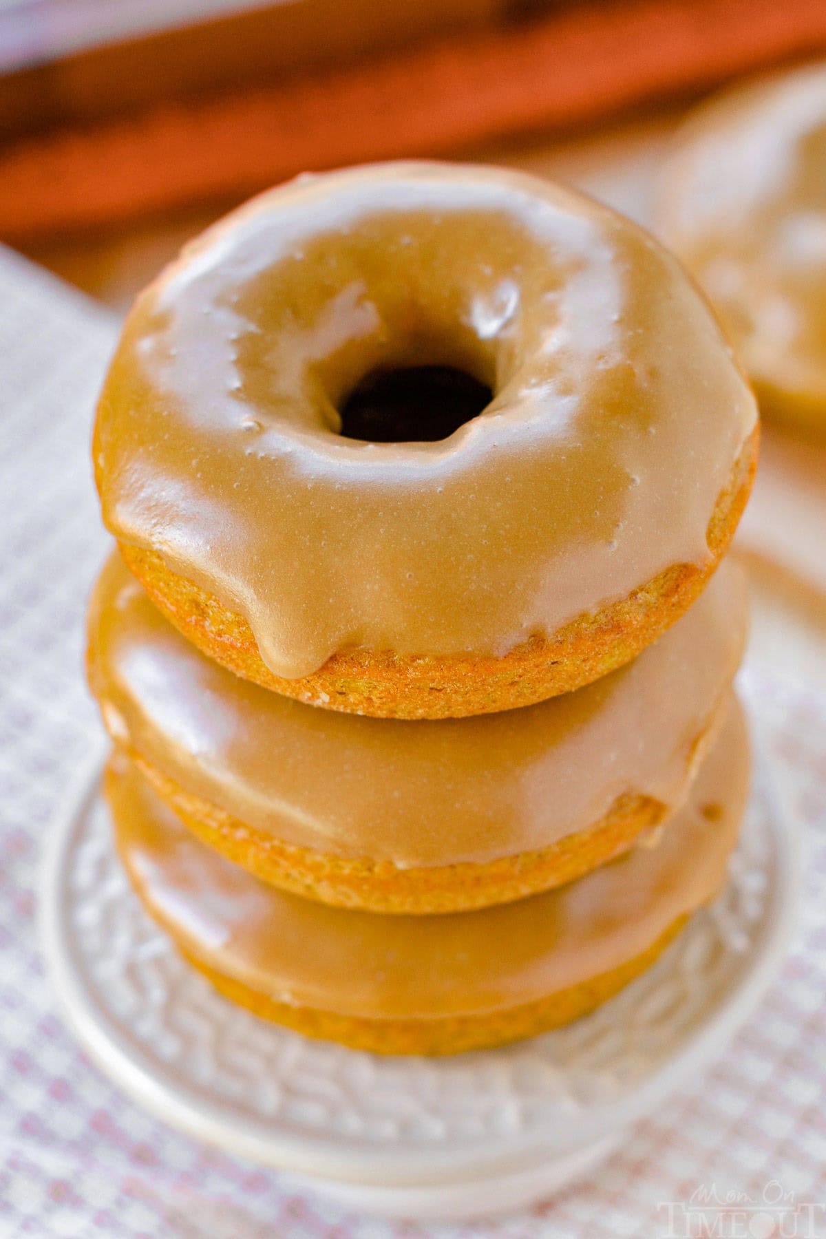 Top down angled view of three baked pumpkin donuts stacked on a cupcake stand.