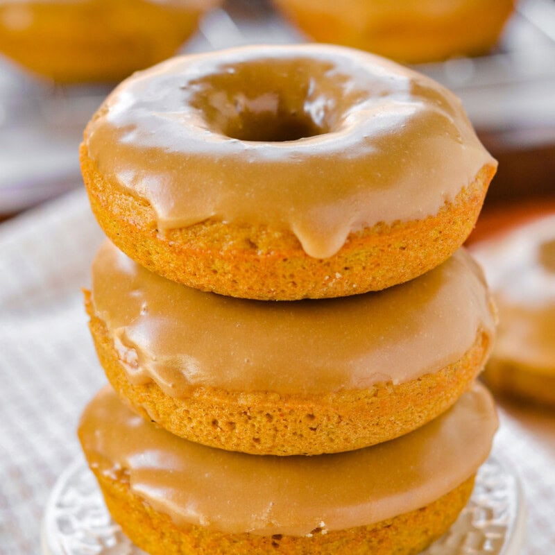 Front view of three baked pumpkin donuts stacked on a cupcake stand.