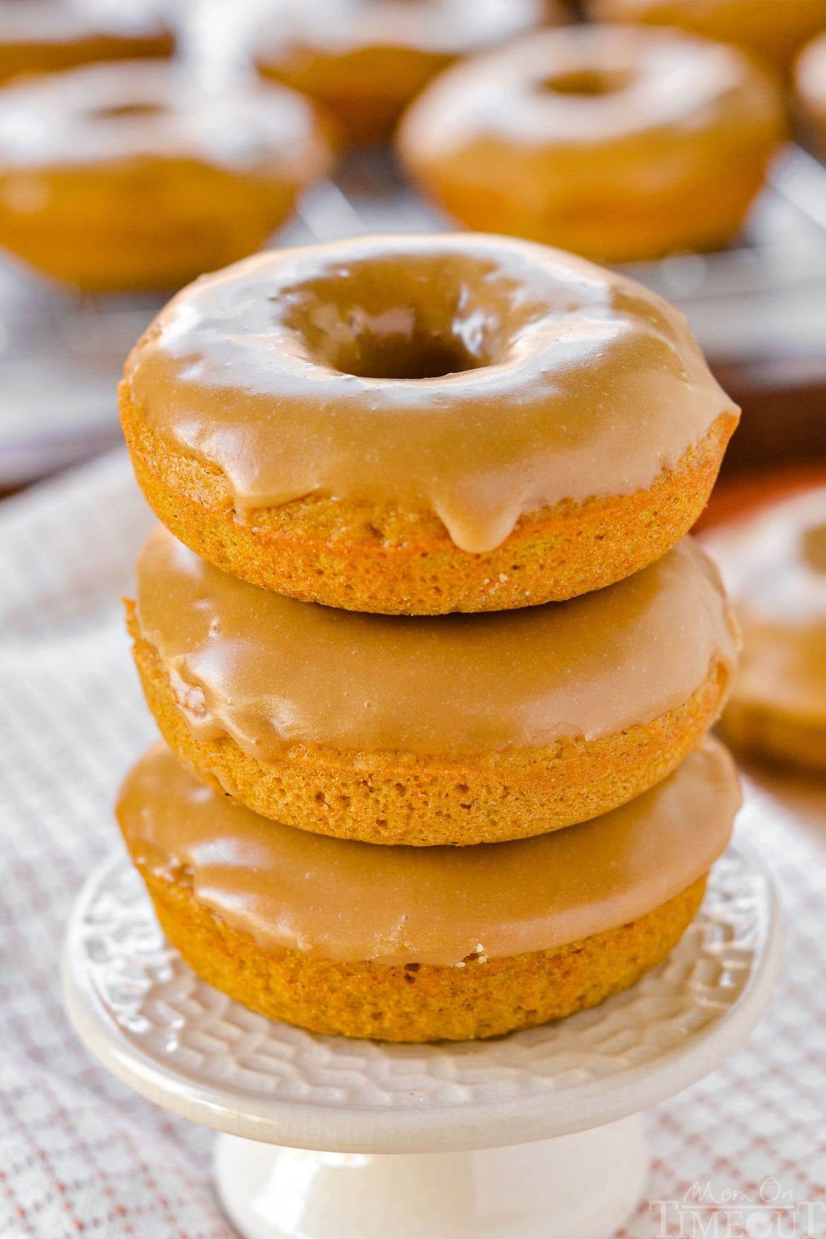 Front view of three baked pumpkin donuts stacked on a cupcake stand.