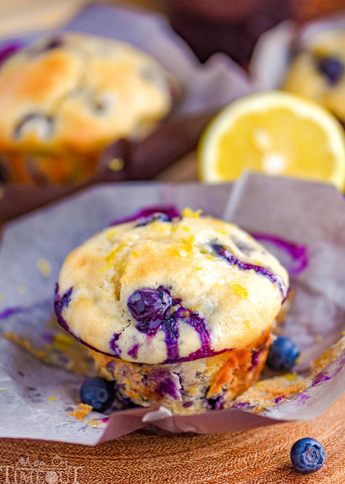 Blueberry Lemon Cream Cheese Muffins topped with a lemon glaze resting on parchment liner.