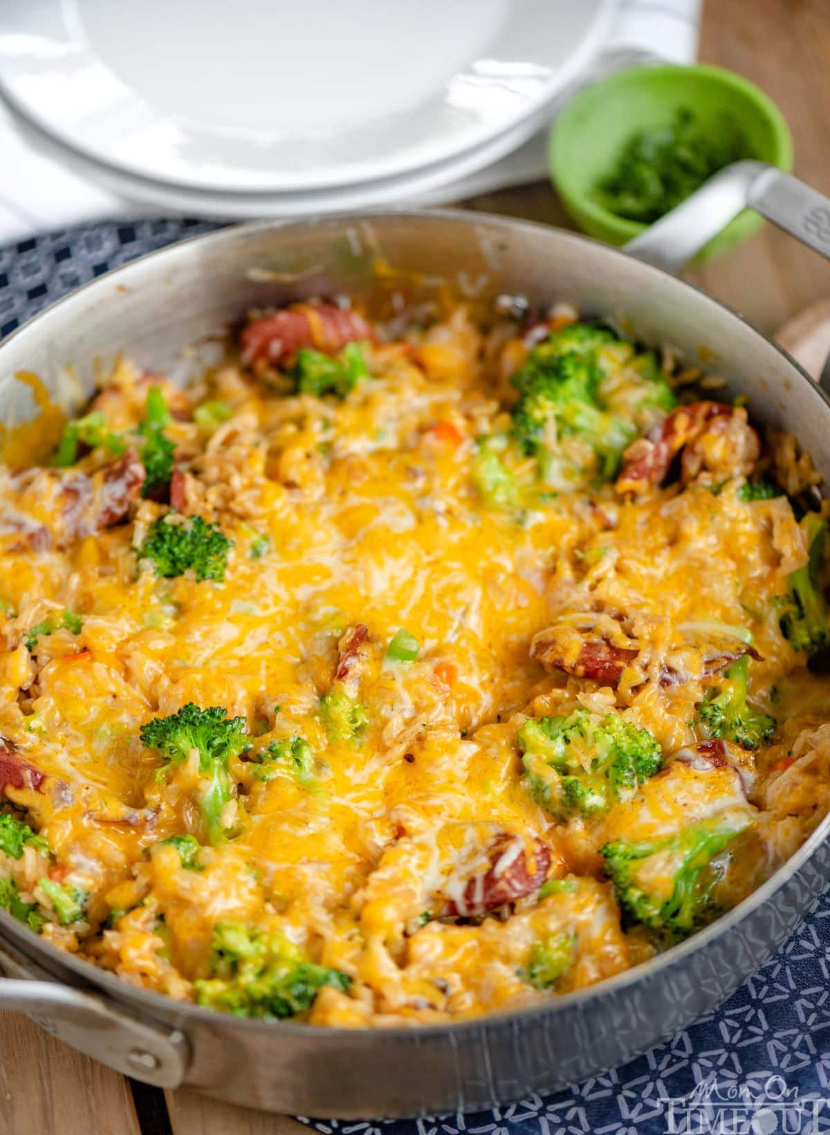 Angled look down at a skillet dinner topped with melted cheese ready to be served and enjoyed. Broccoli, rice and kielbasa can be seen under the cheese.