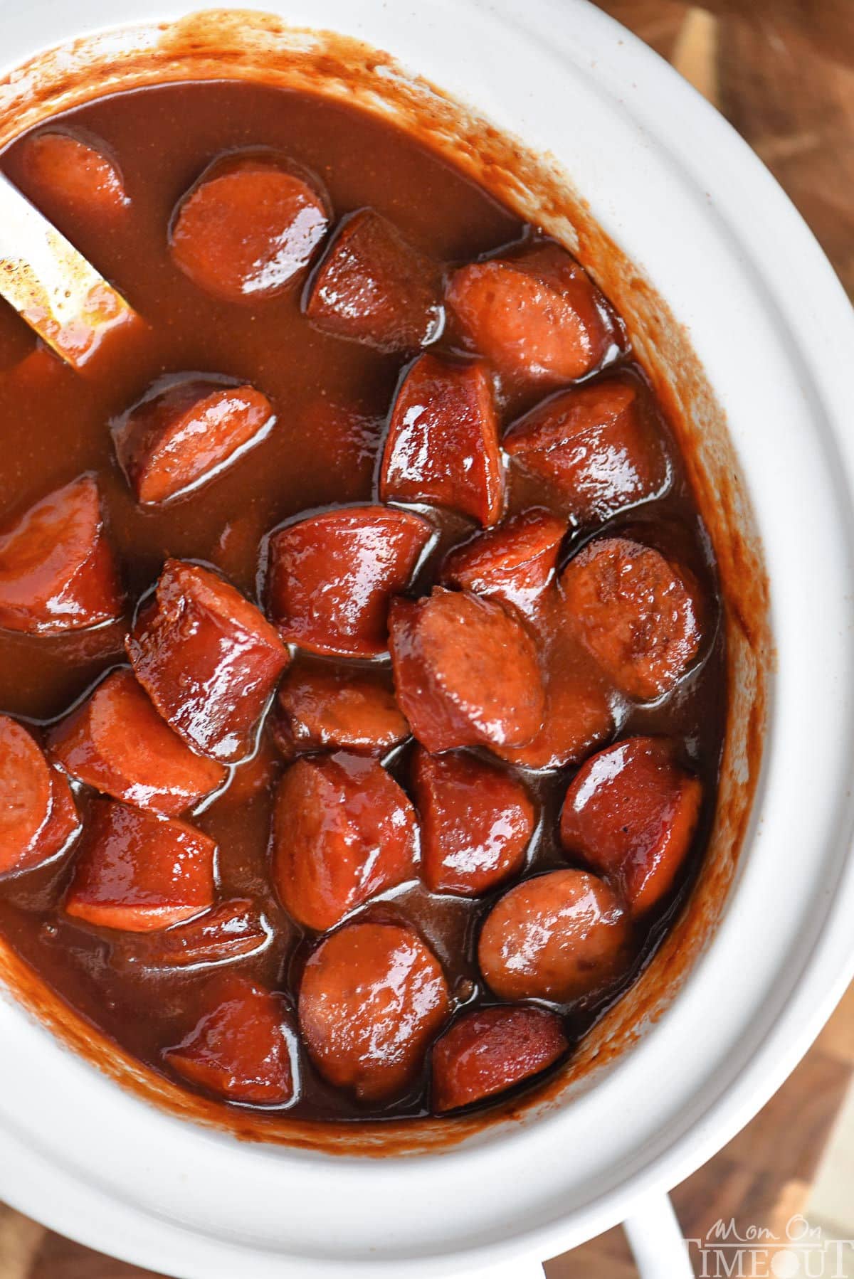 Top down look at white slow cooker full of kielbasa in a sauce made of chili sauce, bbq sauce and grape jelly.