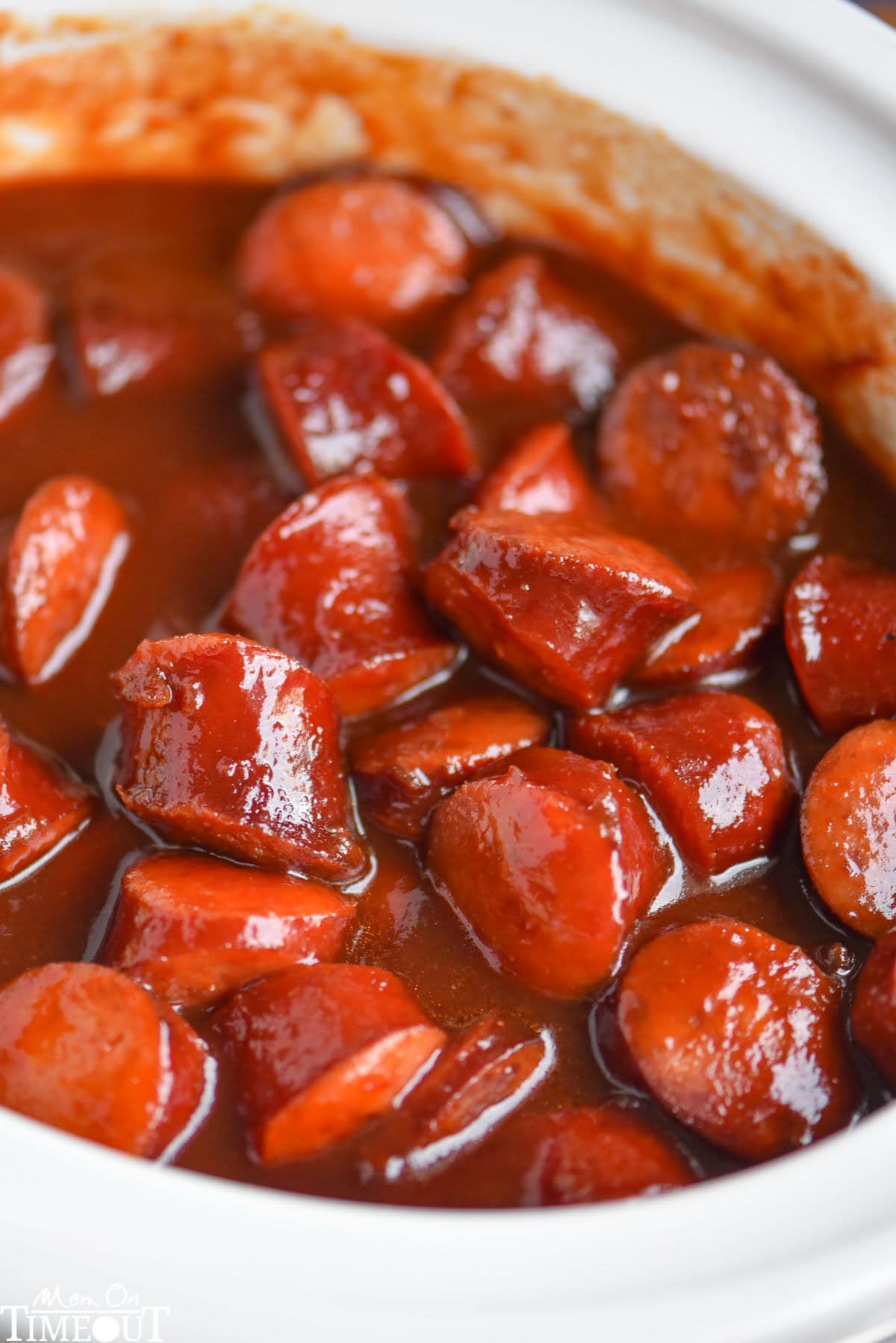 Top down look at white slow cooker full of kielbasa in a sauce made of chili sauce, bbq sauce and grape jelly.