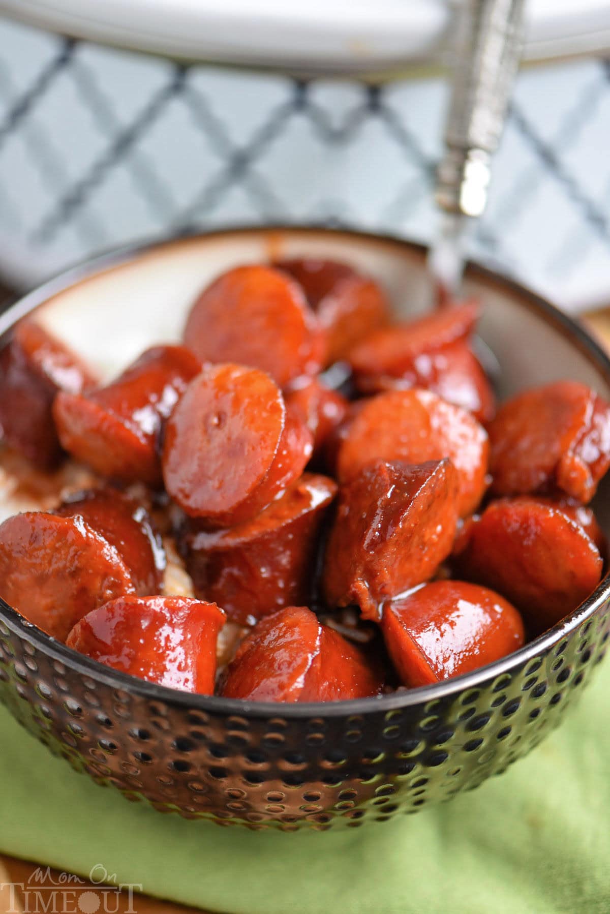 Slow cooker kielbasa bites in a bowl with rice. Slow cooker can be seen in the background.