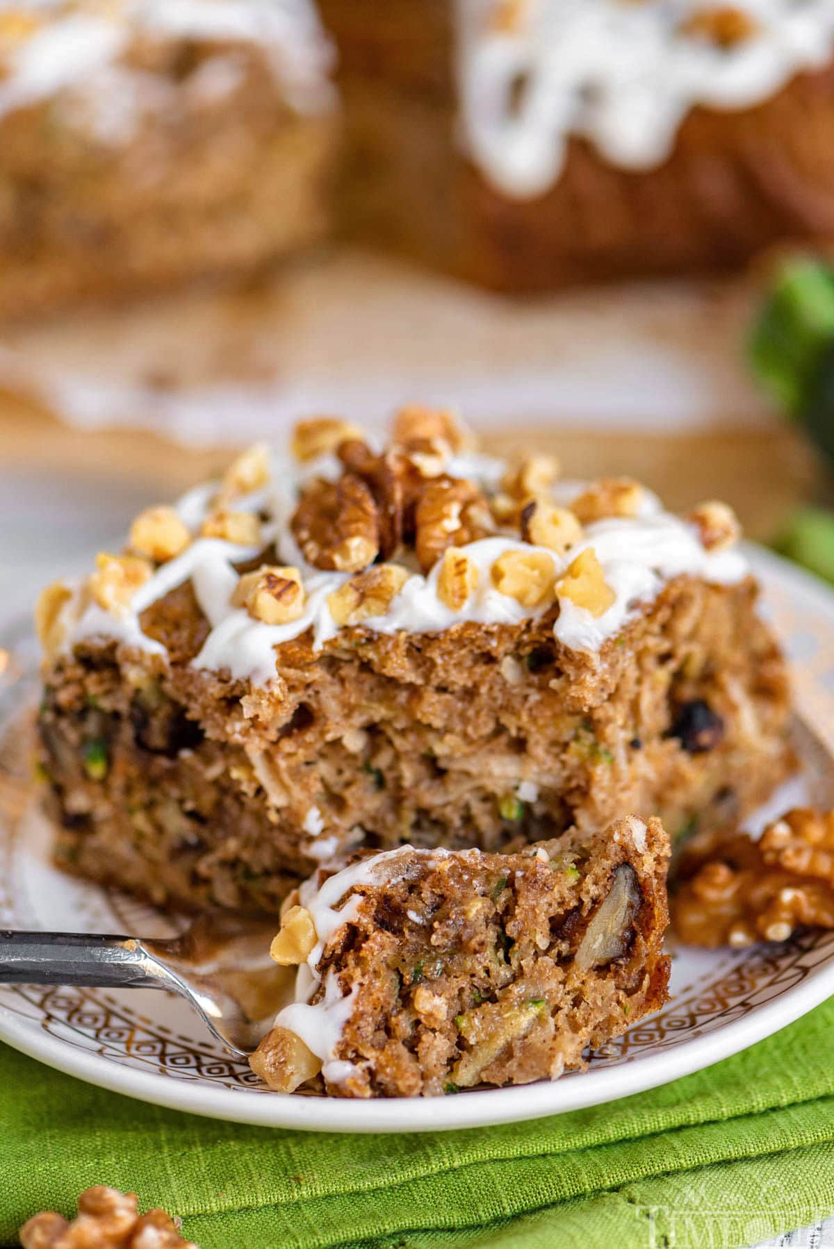 piece of zucchini cake on white round plate with a fork cutting through one corner.