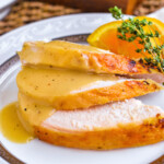 Crockpot turkey breast sliced and plated with turkey gravy on top.