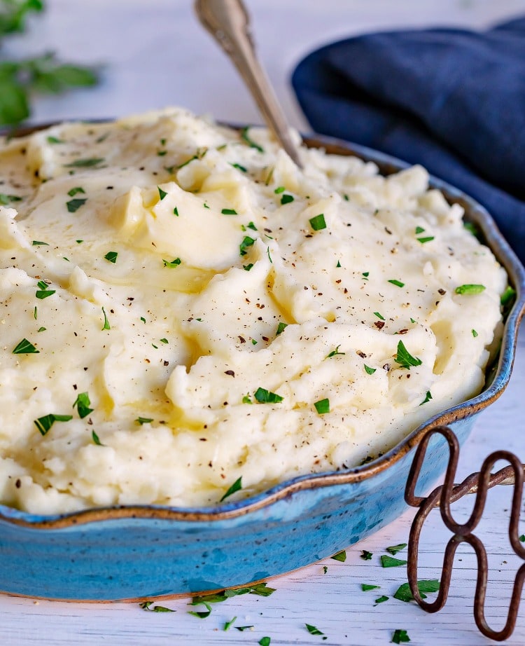 easy mashed potatoes topped with butter in a blue serving bowl