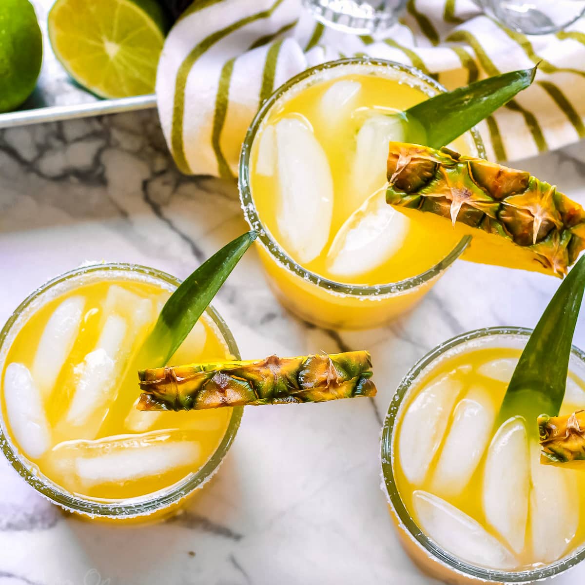 https://www.momontimeout.com/wp-content/uploads/2020/06/pineapple-margaritas-on-marble-cutting-board-with-pineapple-in-the-background-square.jpg