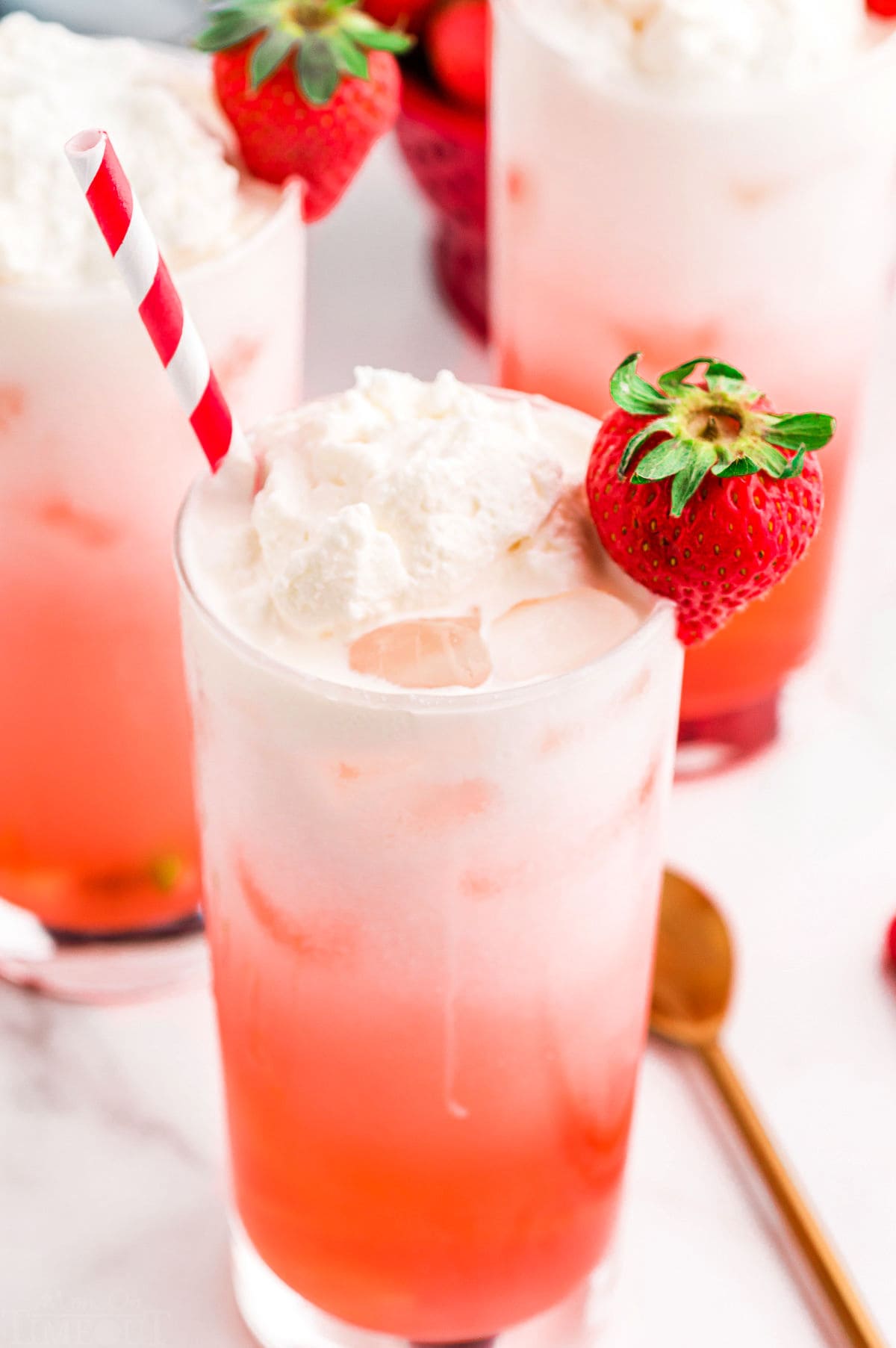 top down look at filled glass with italian soda flavored with strawberry syrup. red and white striped straw in the glass.