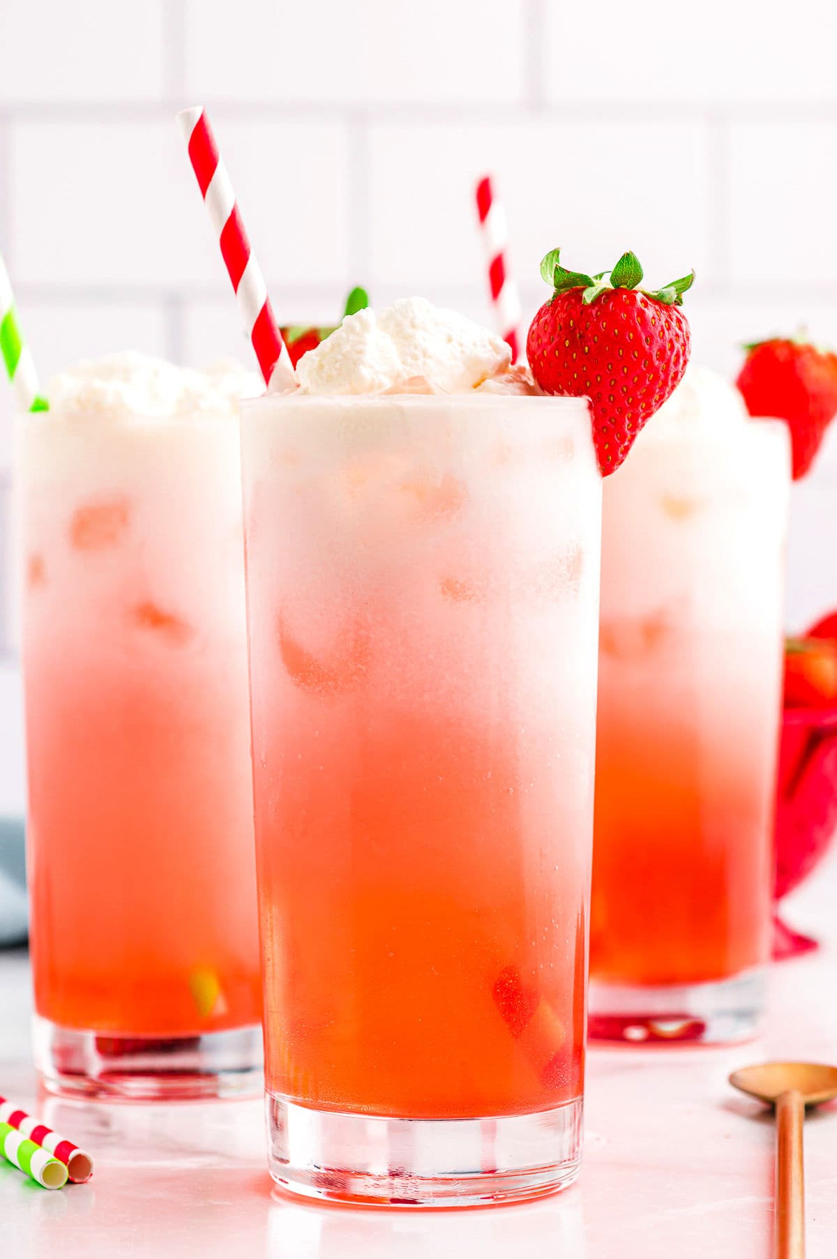 strawberry Italian cream sodas in tall beverage glass with paper straws.