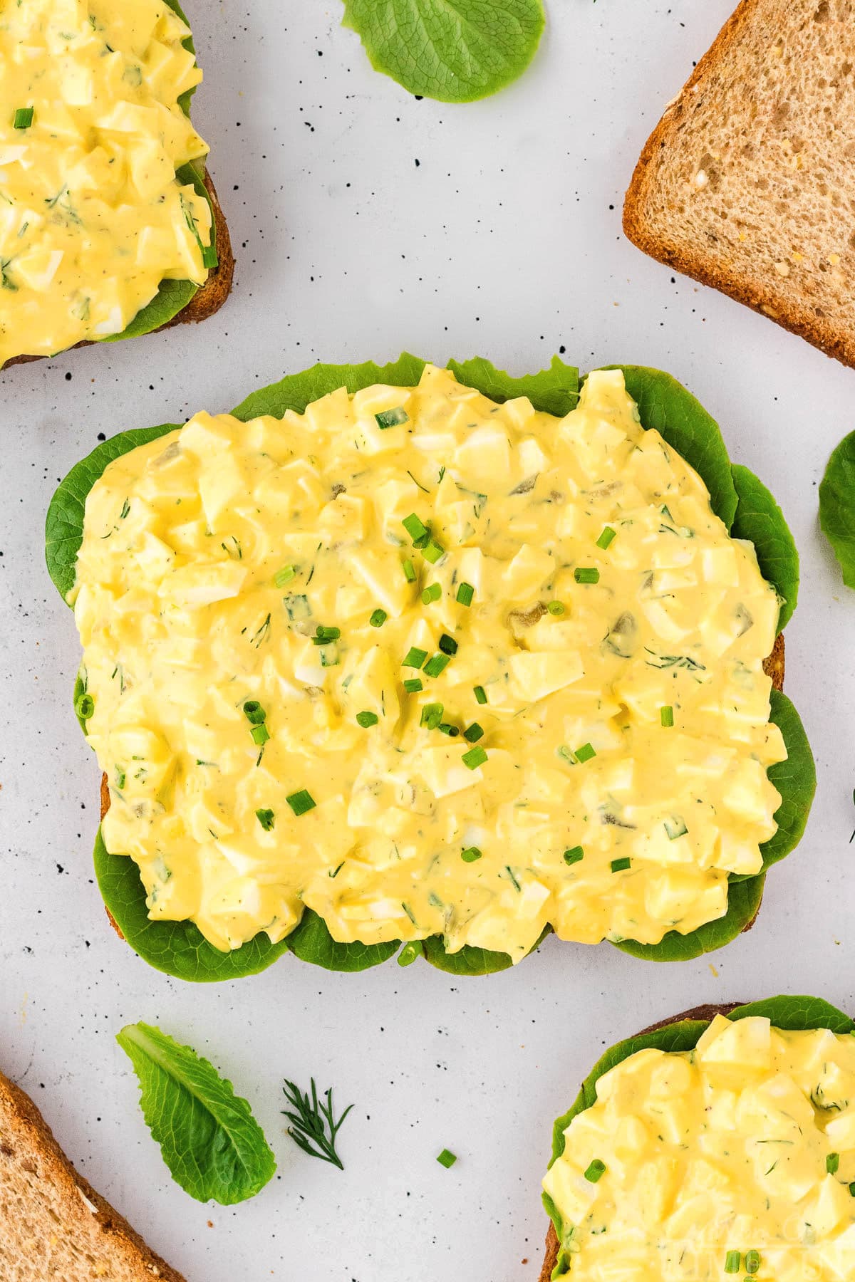 A top down view of egg salad on a piece of bread.
