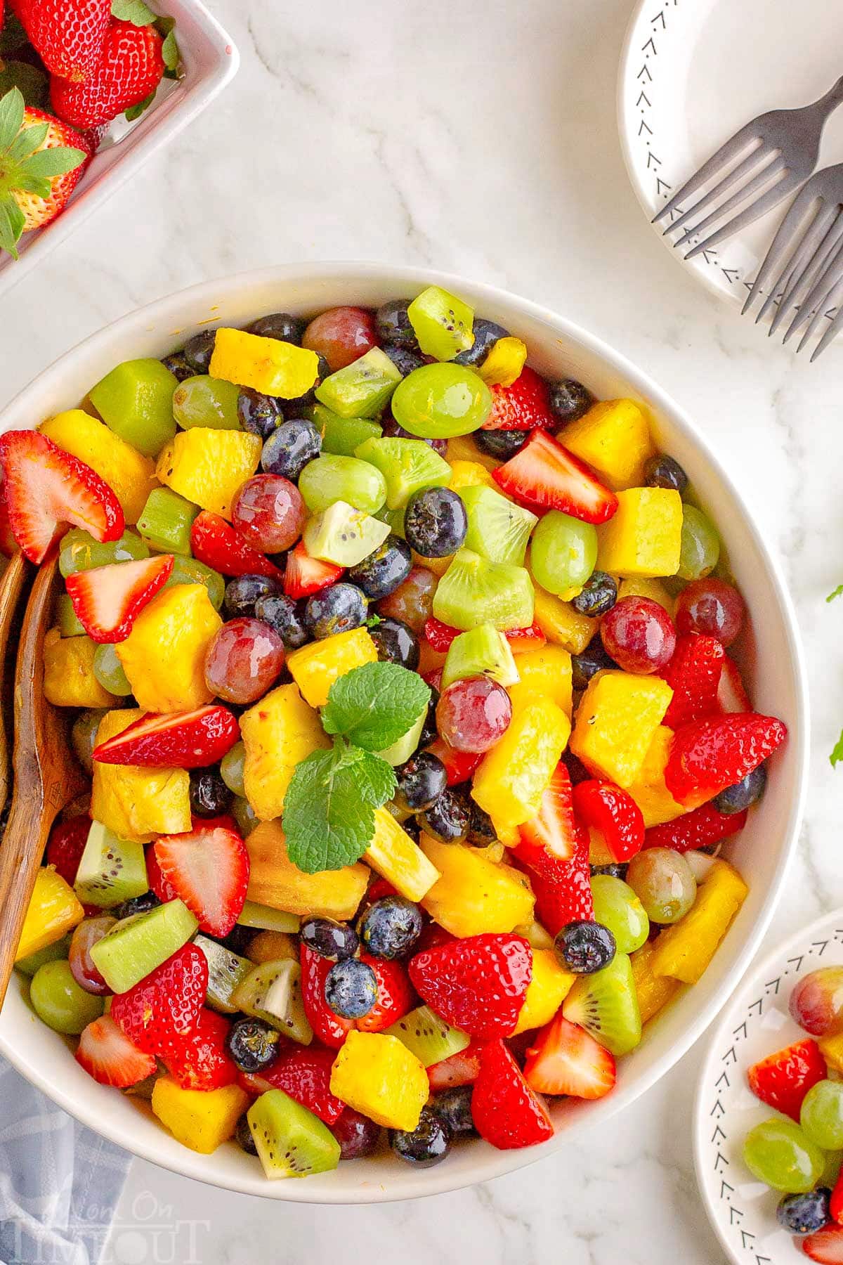 A top down view of a white bowl of fruit salad.