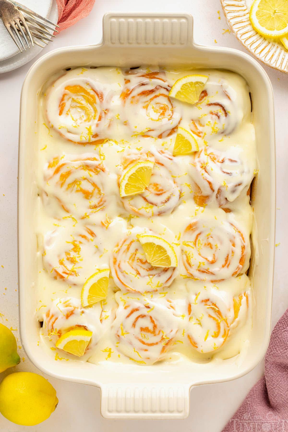 An overhead view of a pan of lemon rolls on a white surface.