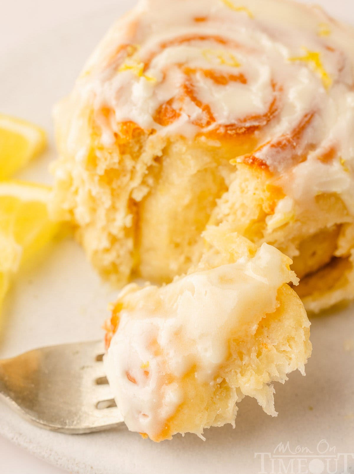 A lemon roll with a fork sitting on a plate next to it.