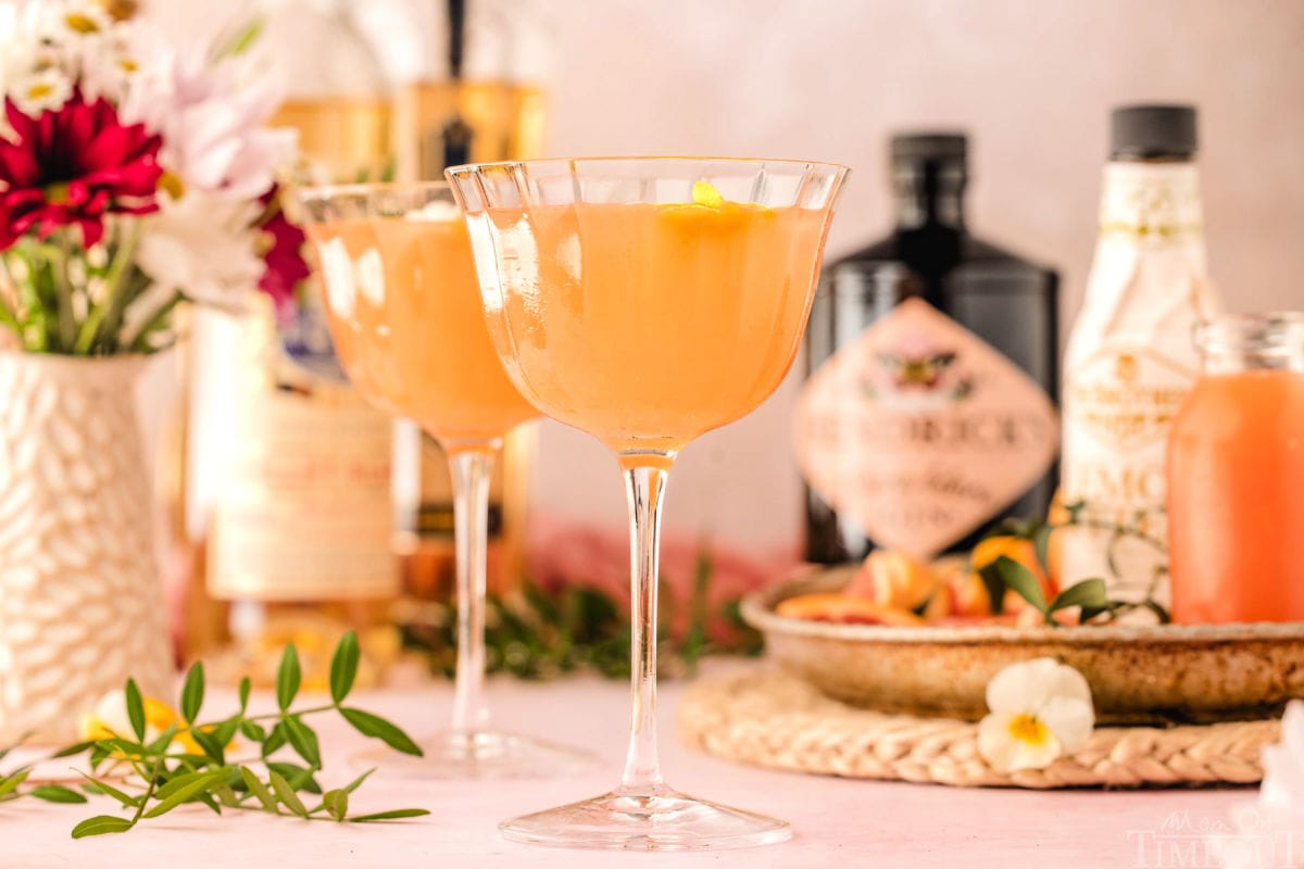 Wide shot of two glasses with french blonde cocktails in them and the bottles in the background.