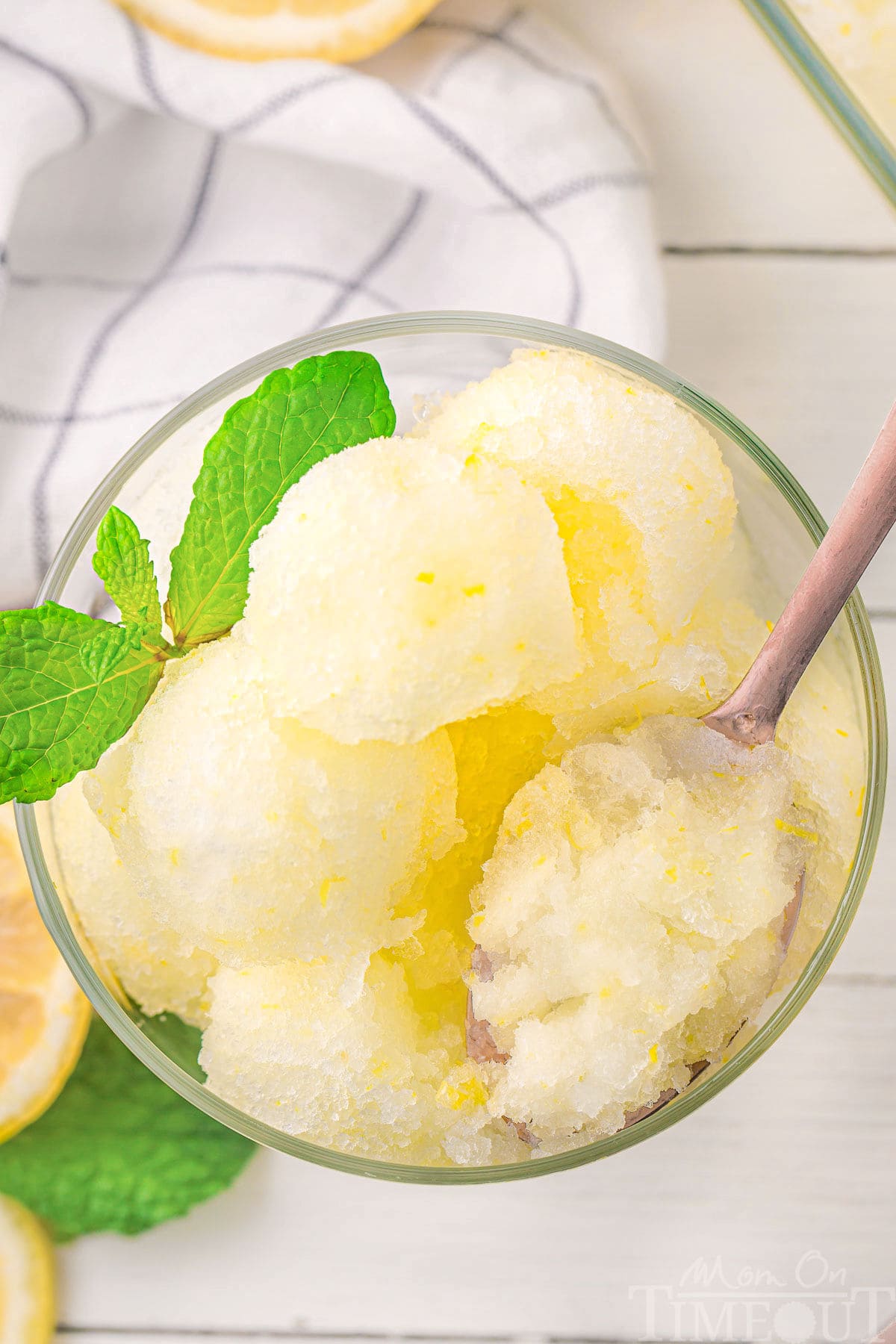 A top down view of a glass of lemon sorbet with a spoon scooping some of it.