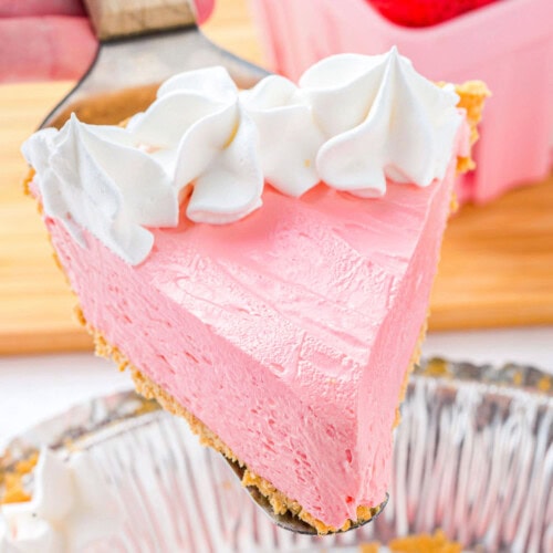 Piece of kool aid pie topped with whipped cream being held up over the rest of the pie.