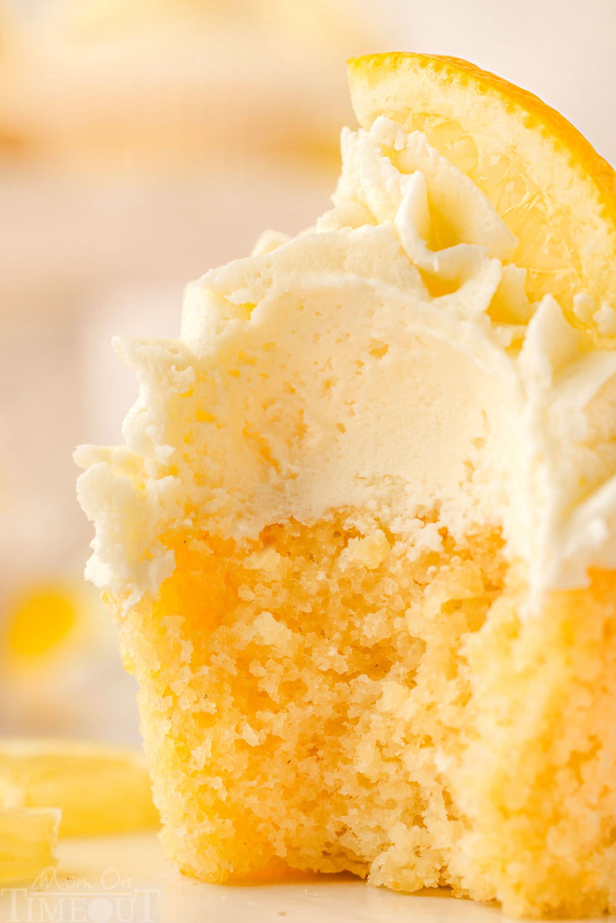 Close up of a lemon cupcake with a bite taken out of it.