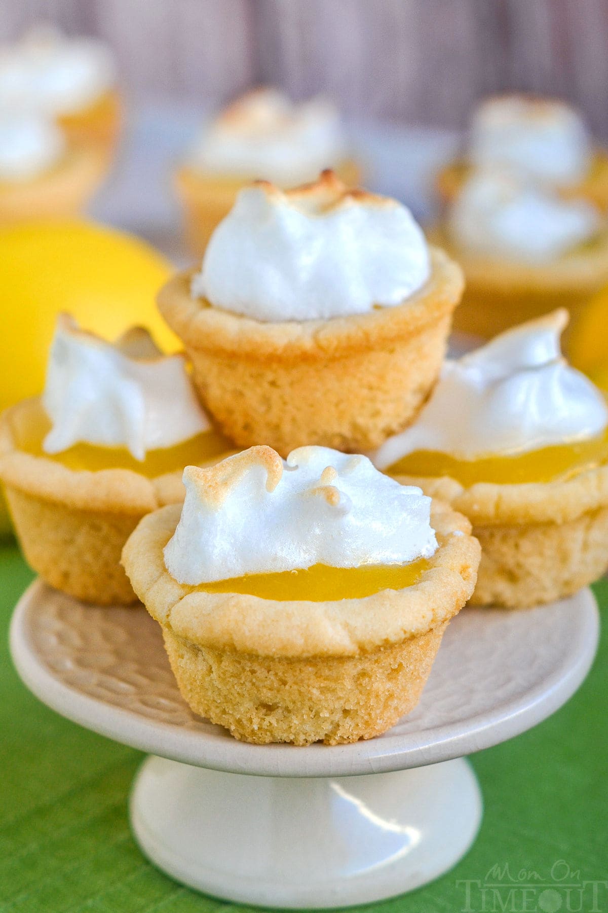 A stack of lemon meringue cookie cups on a white cake stand.