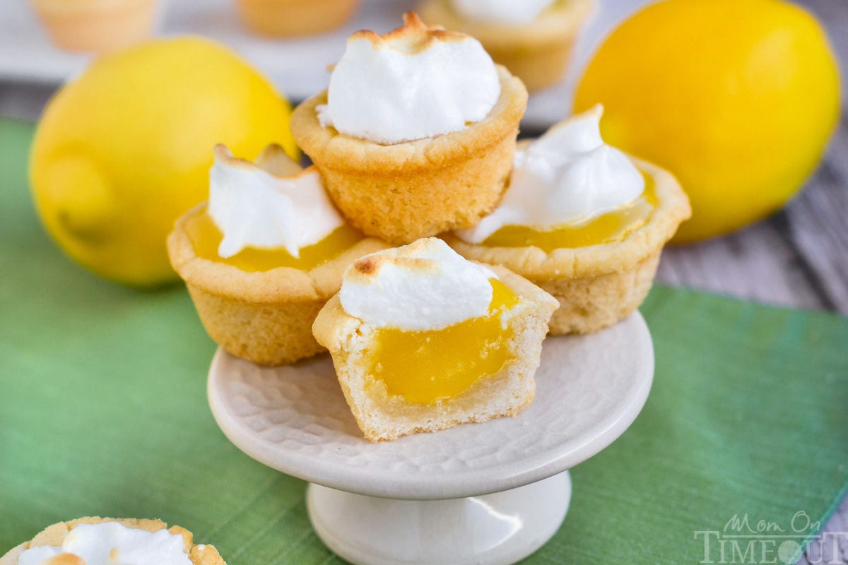A stack of lemon meringue cookie cups no a white cake stand.