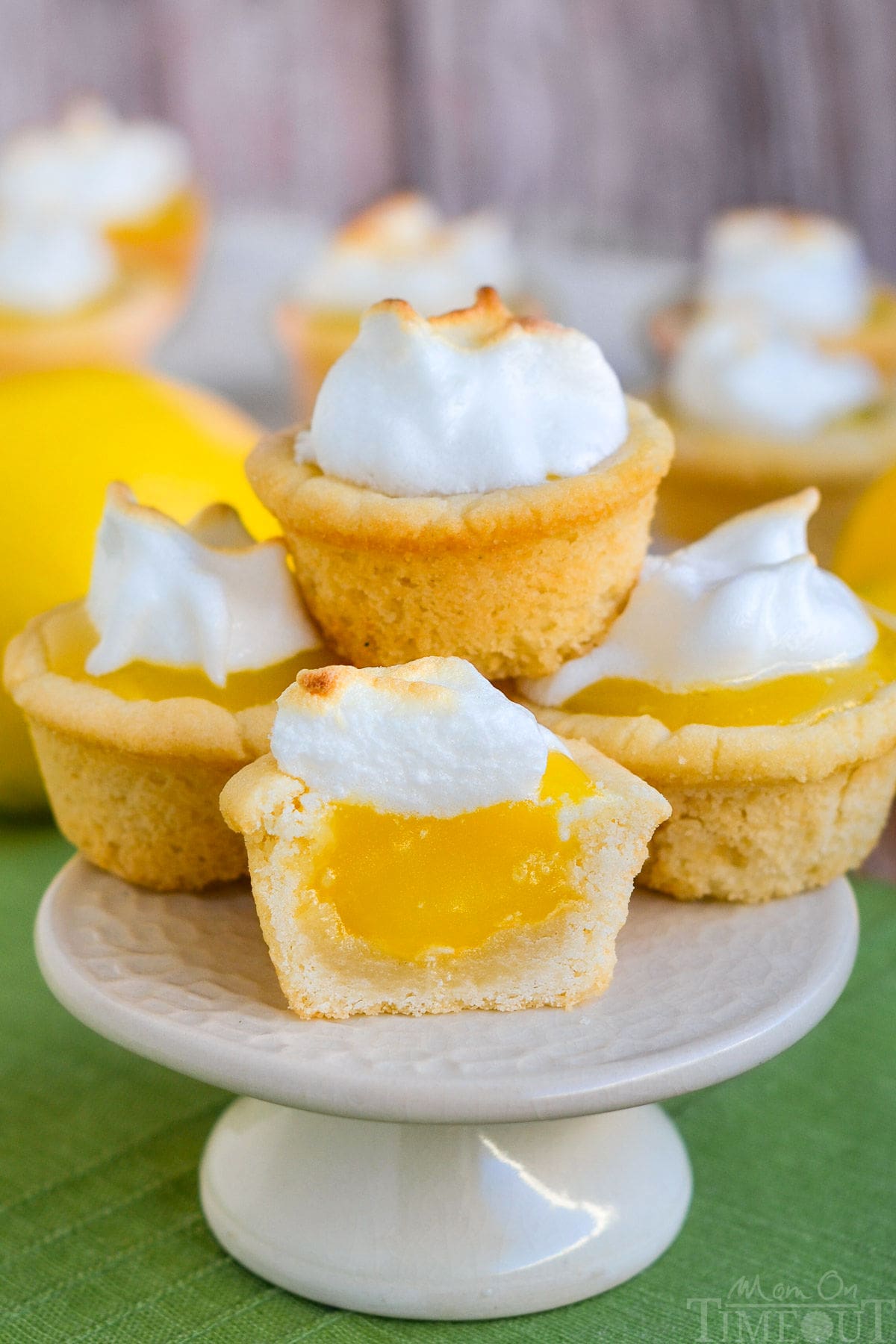 A stack of lemon meringue cookie cups on a white cake stand.