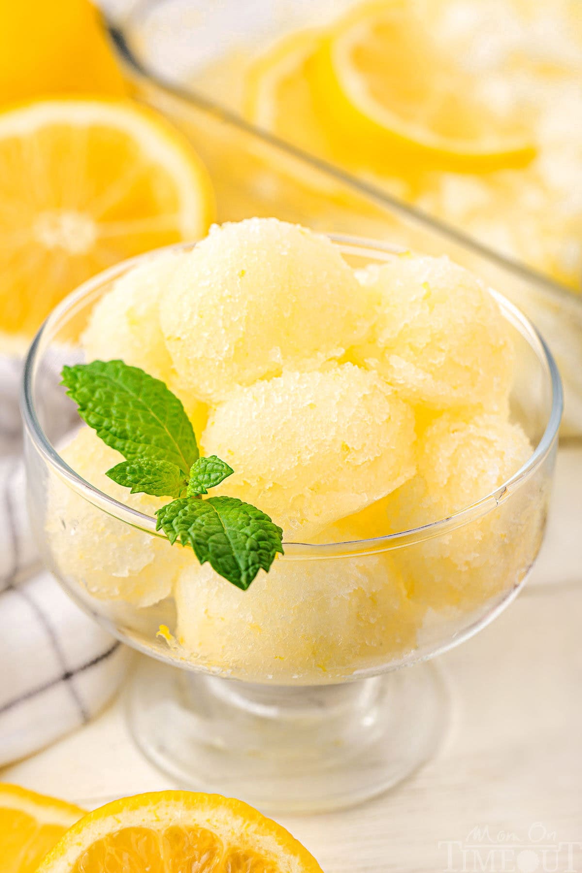 A glass of lemon sorbet with a mint leaf garnishing it.