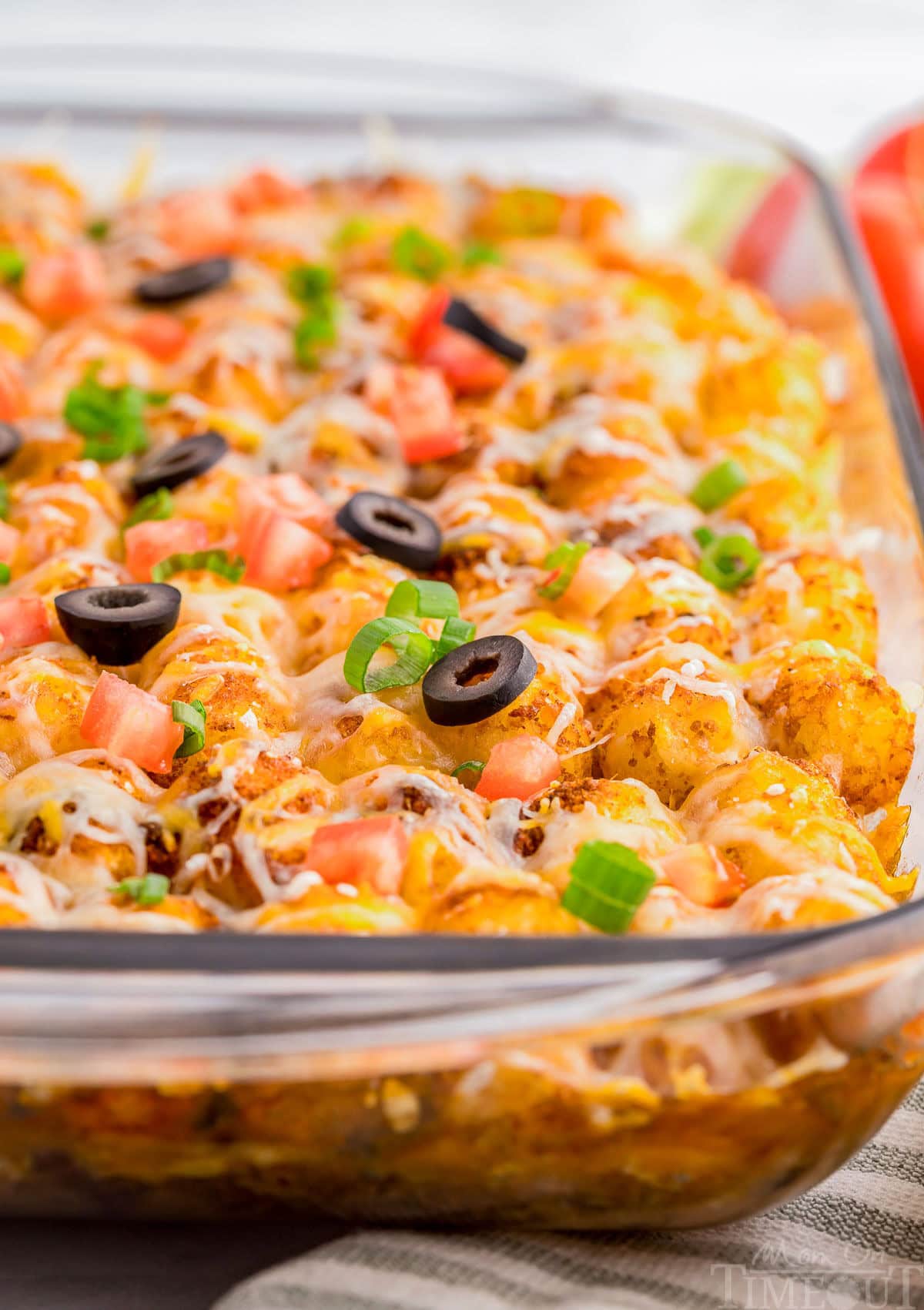 A close up shot of mexican tater tot casserole in a glass pan.