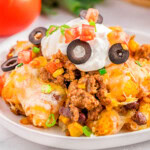 A piece of mexican tater tot casserole on a white plate.