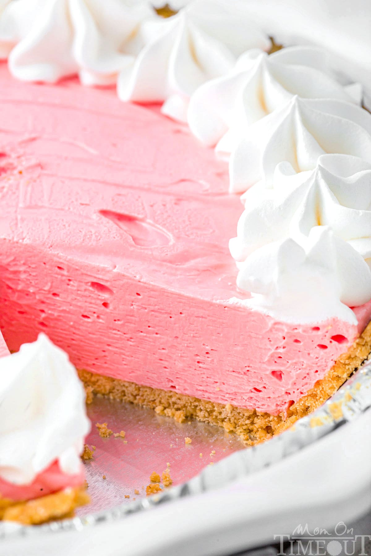Strawberry kool aid pie in a graham cracker crust with one slice removed.