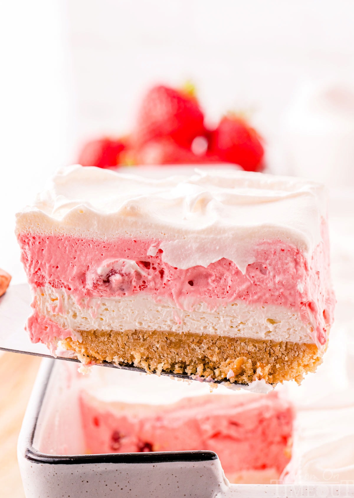 A spatula holding a slice of strawberry lasagna.