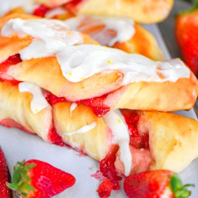 A side shot of Strawberry Twists with strawberries in front of them.