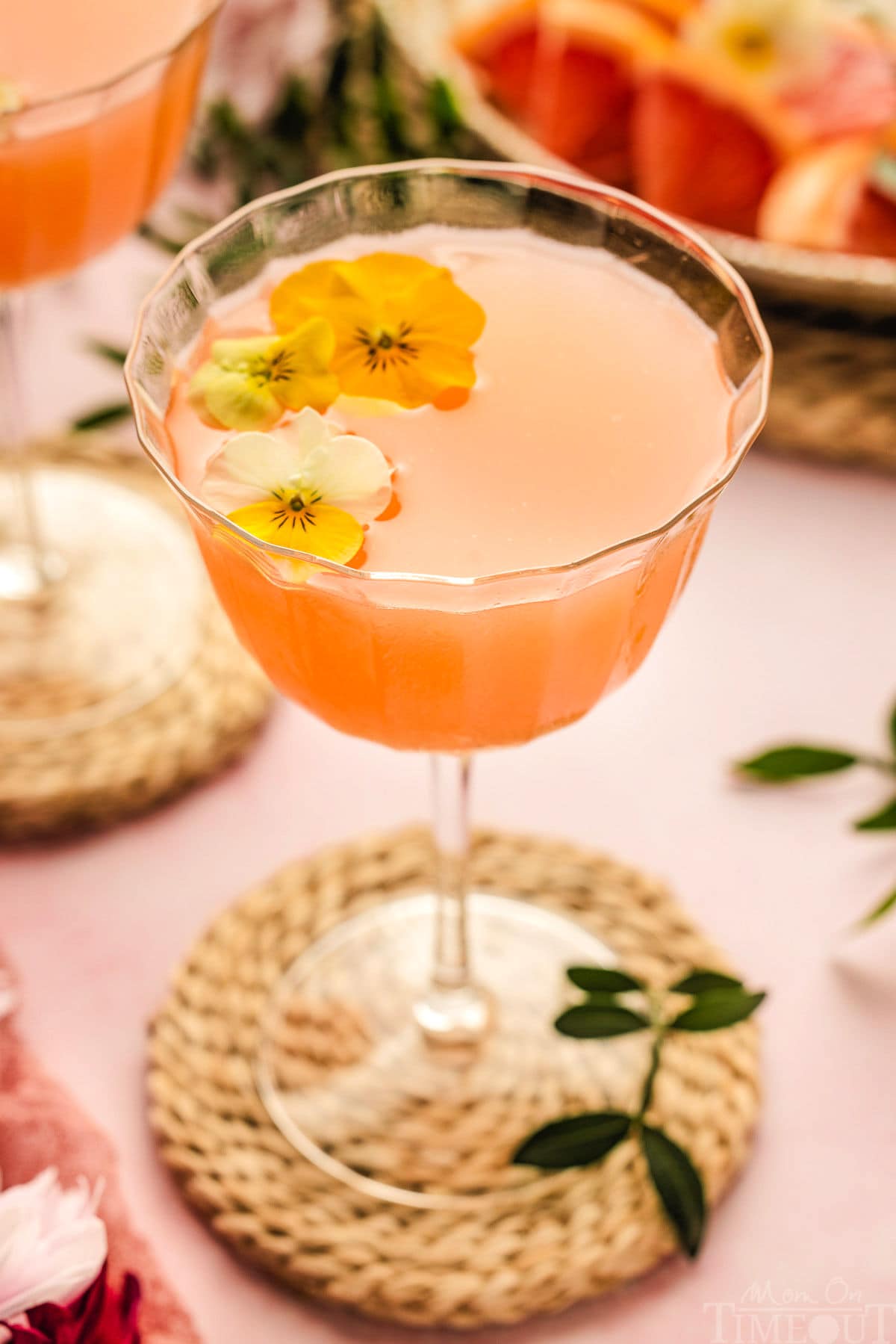 French Blonde Cocktail in a glass with edible flowers as a garnish.