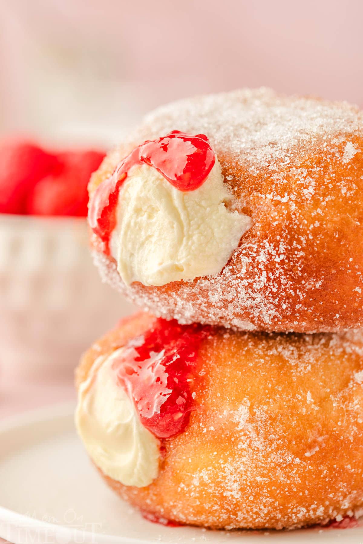 two homemade donuts stuffed with cheesecake and raspberry compote. 