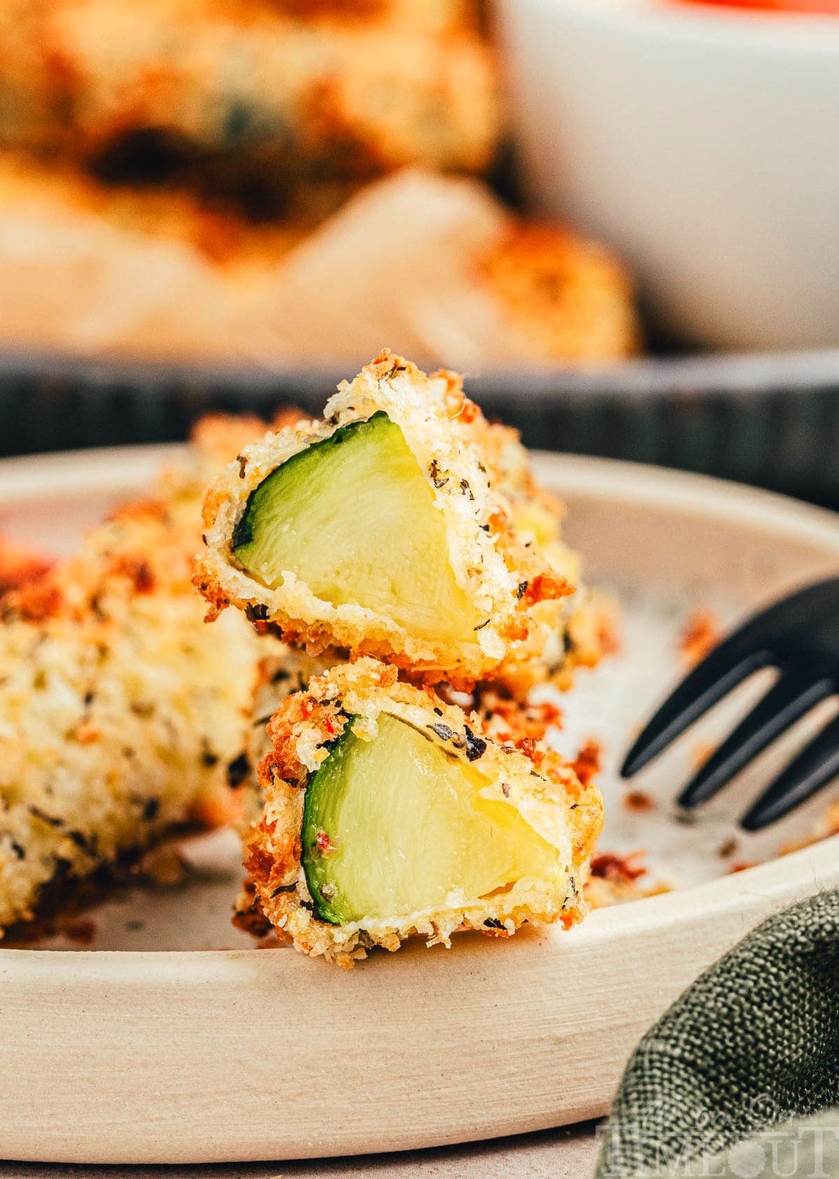 Air fryer zucchini fries cut in half on small plate.