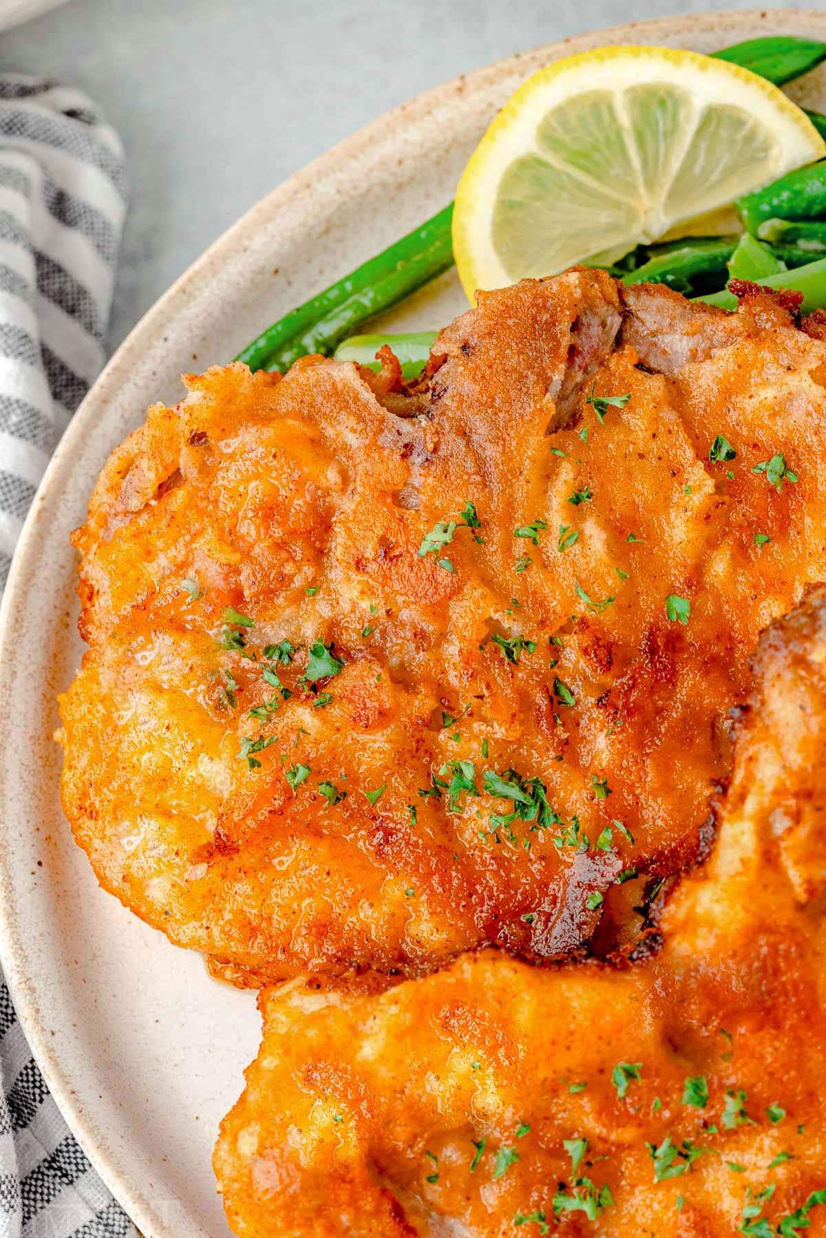 Close up shot of fried pork chops on a white plate.