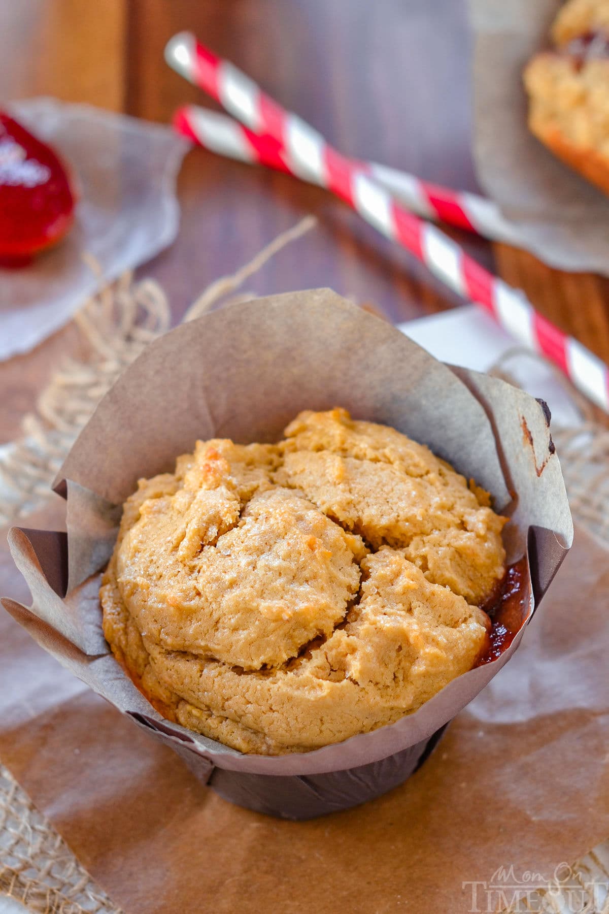 Peanut butter muffin with jelly center in parchment liner ready to be enjoyed.