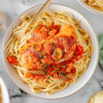 Slow Cooker Chicken Cacciatore on a bed of pasta on a white plate.