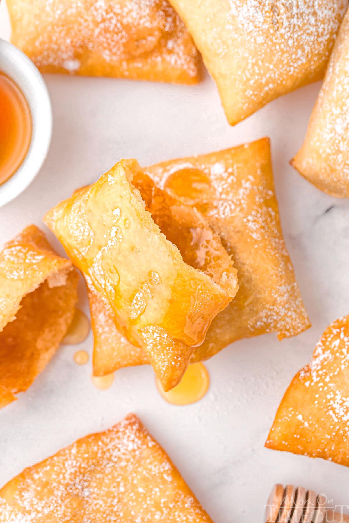 A sopapilla torn in half with additional sopapillas around it on a white surface.