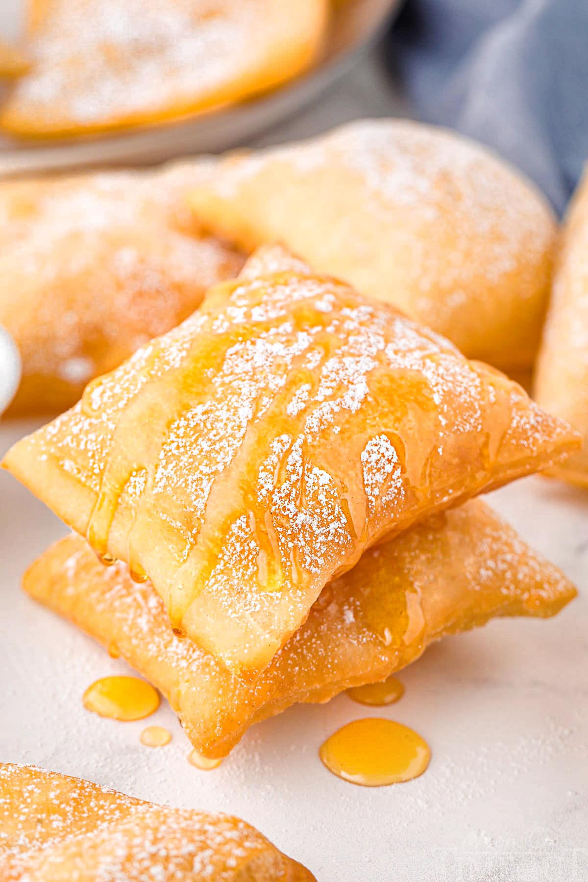 Two sopapillas stacked drizzled honey and topped with powdered sugar.