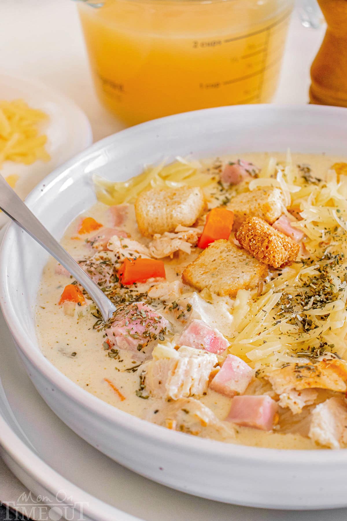 A close up photo of chicken cordon bleu sopu in a white bowl with a spoon in it.