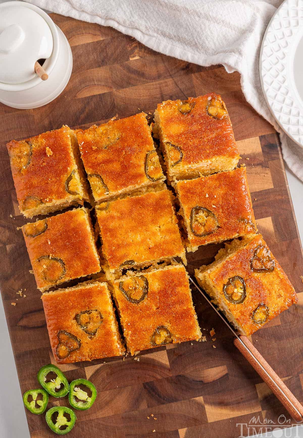 Top down view of jalapeno cornbread on a wood cutting board cut into 9 squares.