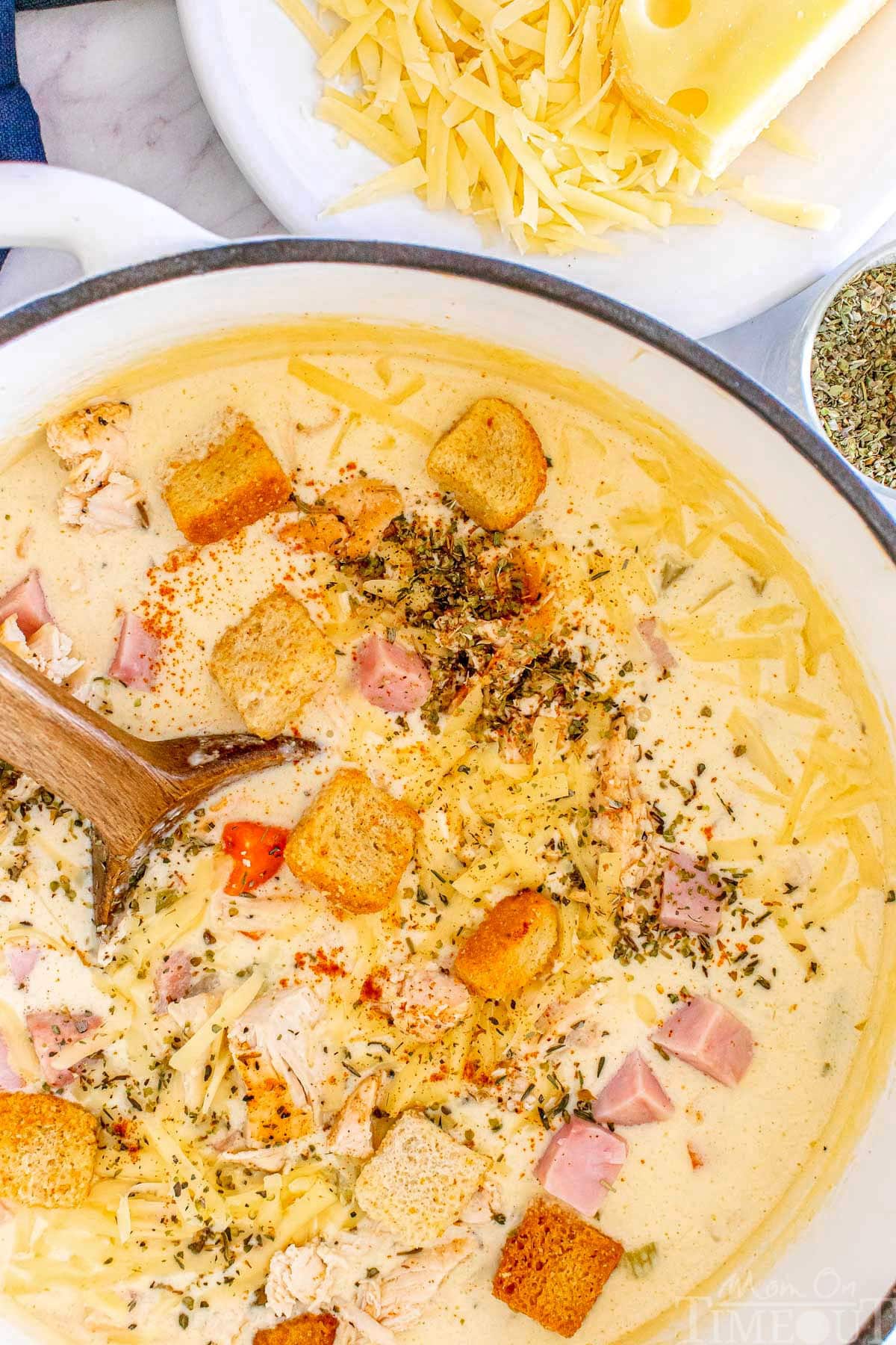 A top down shot of chicken cordon bleu in a dutch oven with a wood spoon in it.