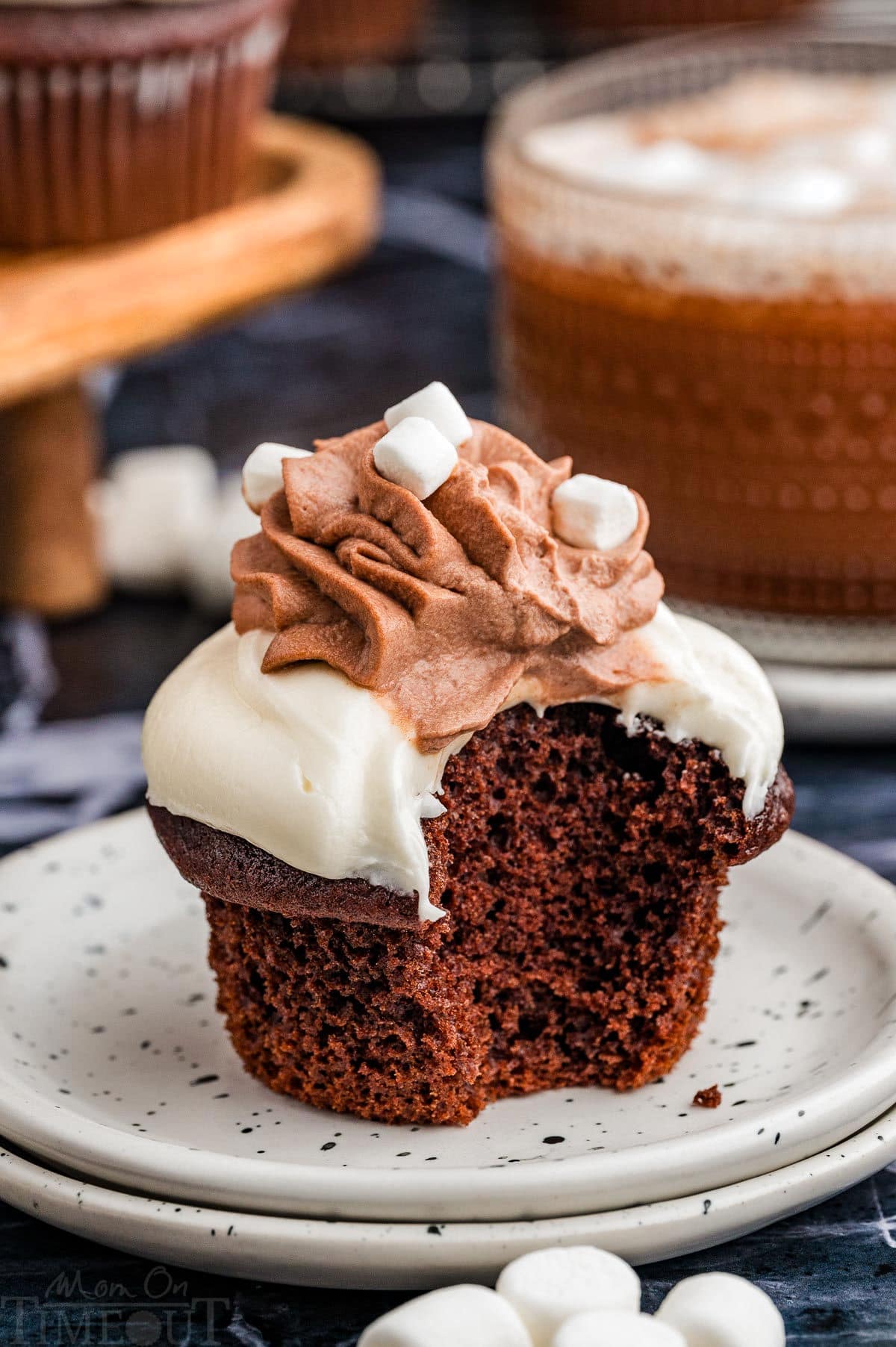 A hot chocolate cupcake on a white plate with a bite taken out of the cupcake.