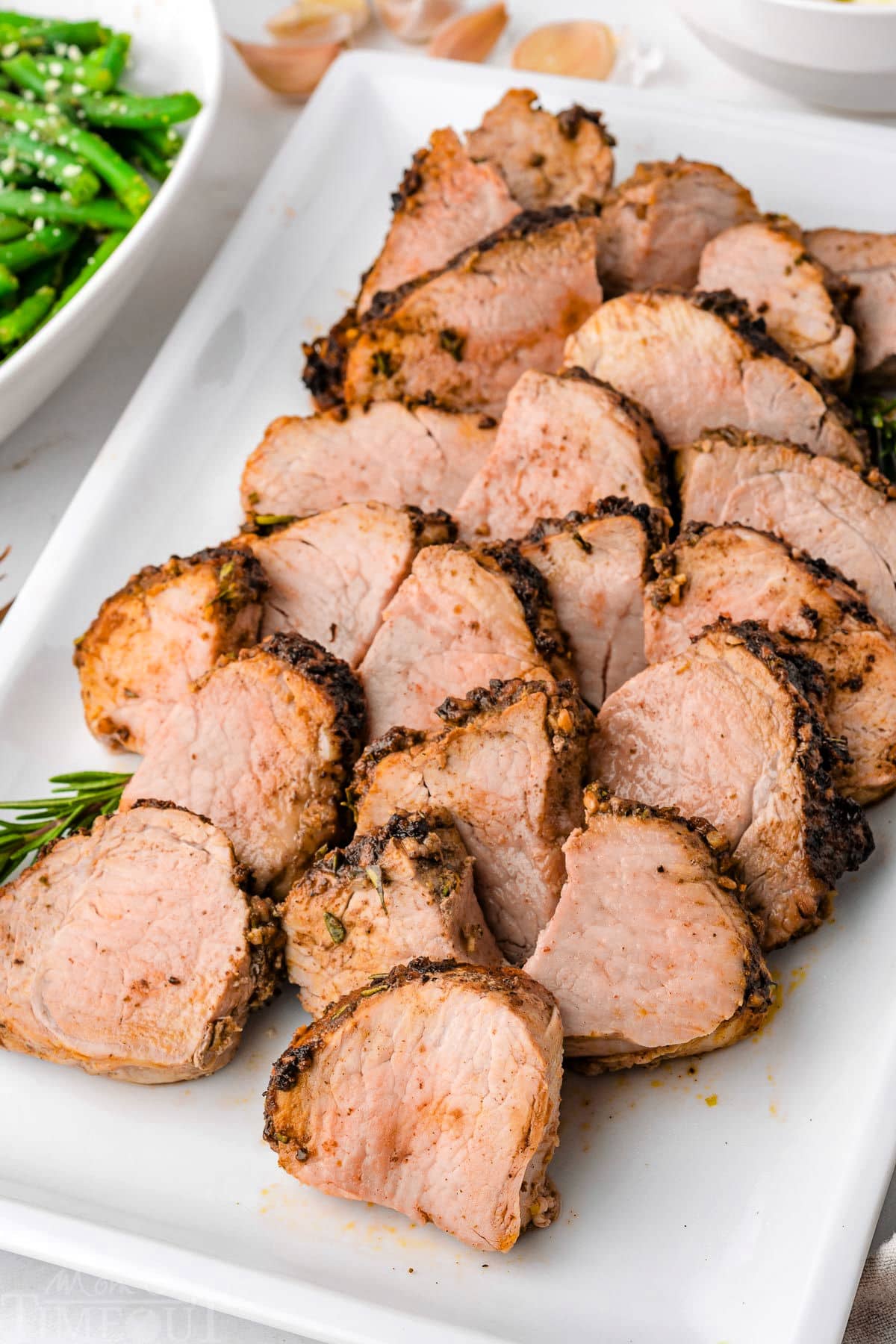 Air fryer pork tenderloin cut into medallions sitting on white rectangular platter.