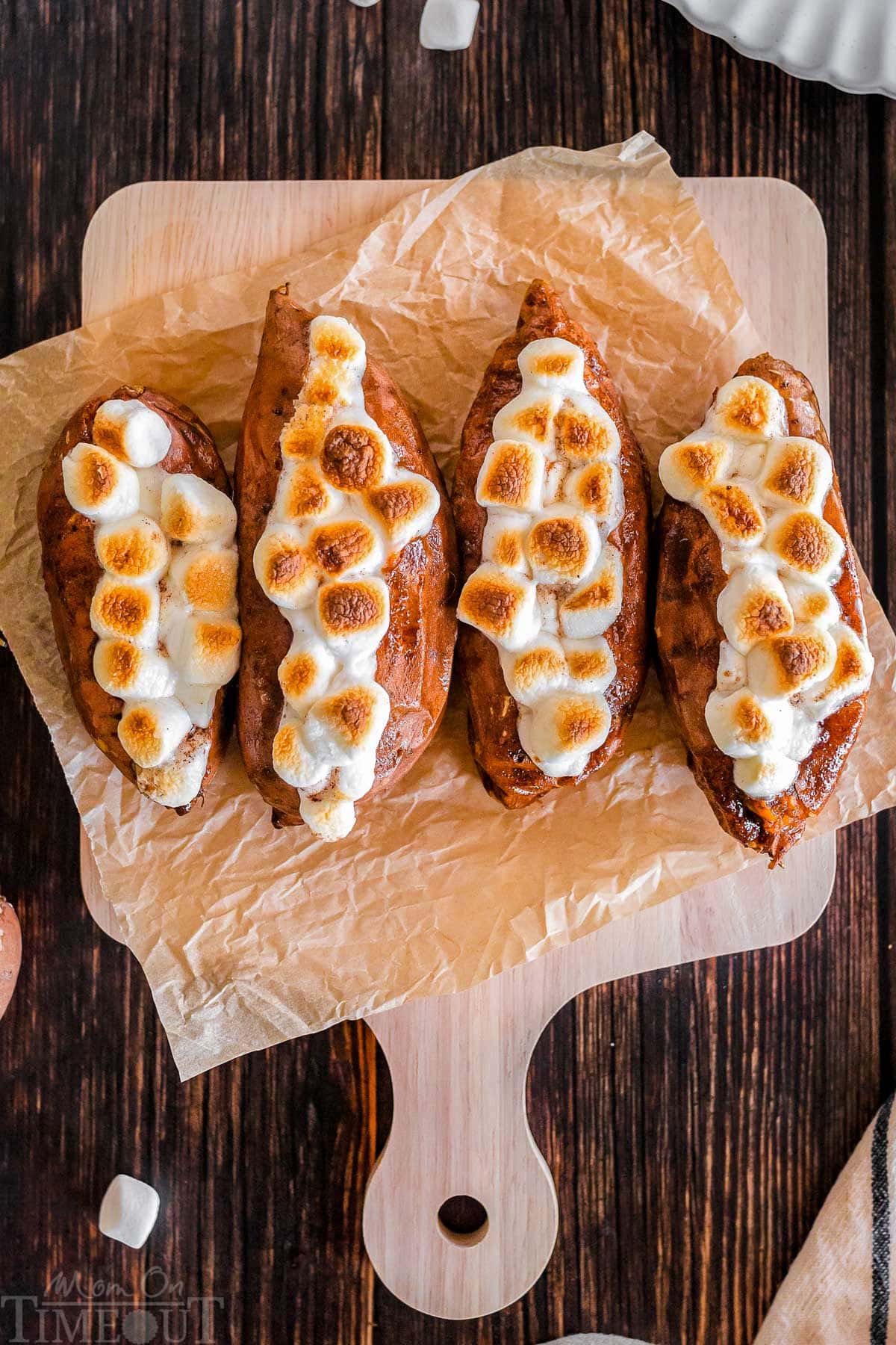 Twice baked sweet potatoes on a piece of parchment paper that's on a wood cutting board.