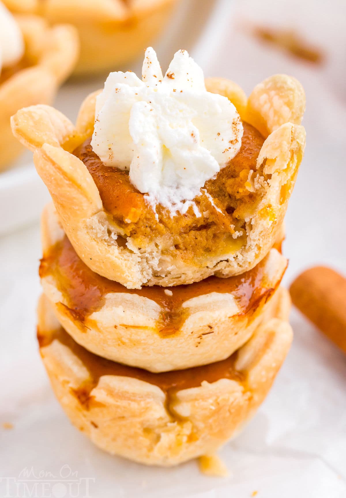 A stack of mini pumpkin pies. The top one has a bite taken out of it.